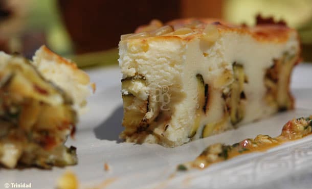 Tranche de gâteau salé aux courgettes et fromage, avec morceaux de courgette bien visibles et pesto en accompagnement