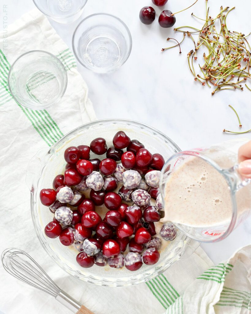 Pâte à clafoutis versée sur les cerises dans un moule beurré
