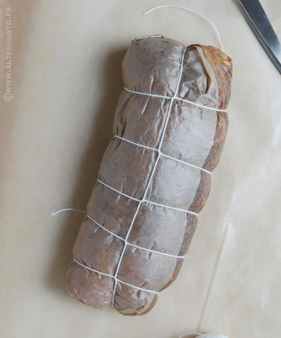Poitrine de dinde enroulée et ficelée dans du papier cuisson avant la 2e feuille
